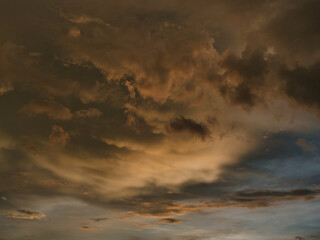 Obraz premium Sunset sky was beautiful, with thick, dark orange and golden clouds near the horizon and dark, warm-toned clouds turning cool blue at the bottom.