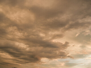 Obraz premium Sunset sky was beautiful, with thick, dark orange and golden clouds near the horizon and dark, warm-toned clouds turning cool blue at the bottom.