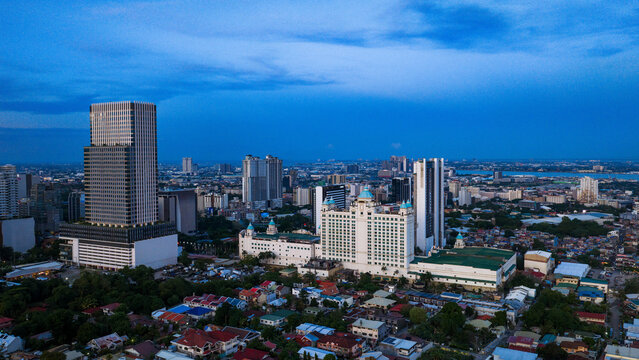 Cebu City, Philippines - 12 June 2026: Aerial view of the urban skyline featuring modern skyscrapers and the white facade of the Waterfront Cebu City Hotel under a deep blue twilight sky.