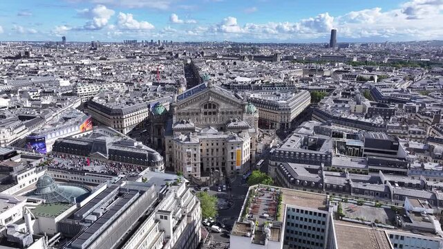 Technical aerial shot combines a lateral movement left with a smooth counter-pan right to maintain focus on the central Palais Garnier building and Paris skyline.
