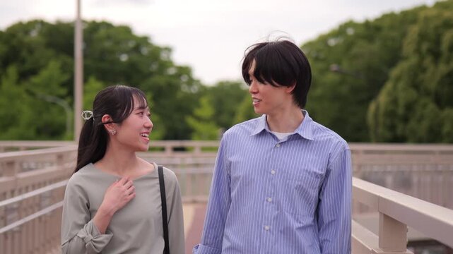 話しながら歩道橋を歩くカップルのトラッキングショット