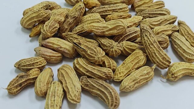 Group of boiled peanuts in shells scattered on white background.