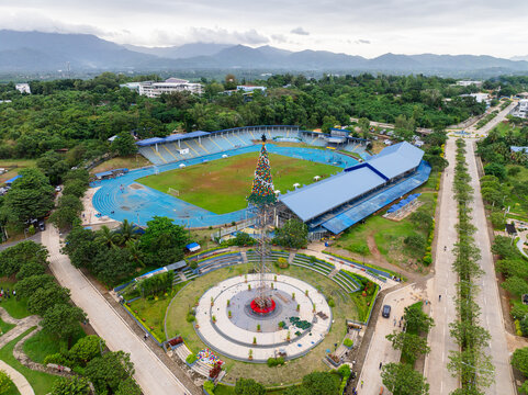 Puerto Princesa City, Philippines - 16 November 2025: Aerial view of Balayong Rotonda Park with tall Christmas tree structure next to a sports stadium with a blue running track.