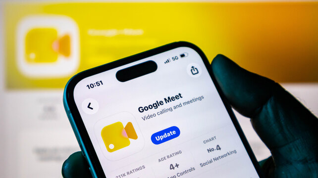 Closeup of a hand holding a smartphone displaying the google meet app update page on the apple app store