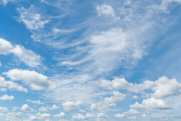 Fototapeta premium White wispy cirrus and fluffy cumulus clouds scattered over a bright blue sky