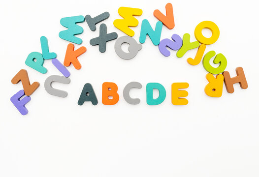 Top View Studio Shot of Colorful Wooden Alphabet Letters Arranged on White Background