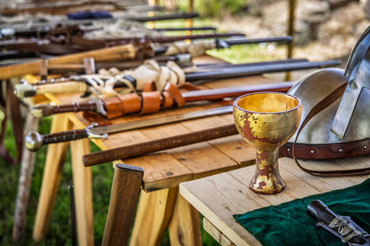 Collection of historical medieval weapons and armor laid out on a wooden table