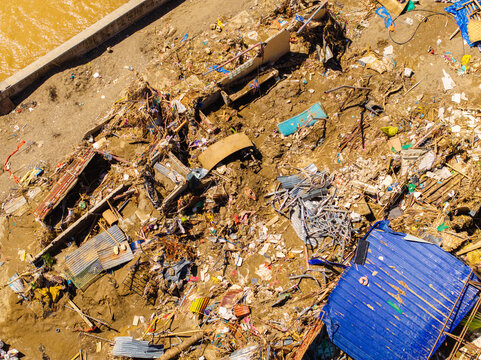 Talisay, Philippines - 11 November 2025: Aerial view of the devastating aftermath of a flood showing destroyed homes, scattered debris, and thick mud along a riverbank.