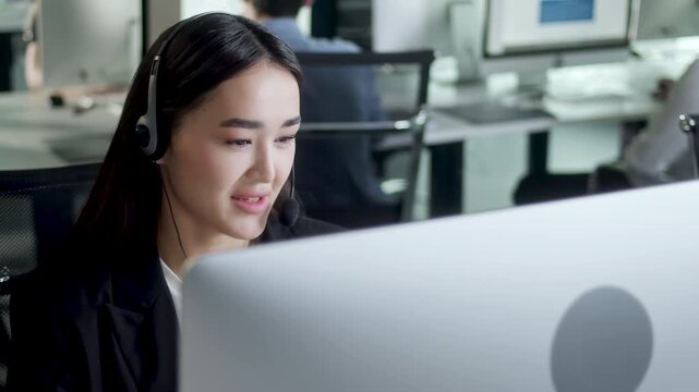 Close up of young female customer support agent wearing headset and speaking with client in a modern call center office. Professional businesswoman provides online assistance and customer service