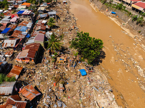Talisay, Philippines - 11 November 2025: Aerial view of the aftermath of a flood showing a muddy river and destroyed houses with debris scattered along the riverbank.