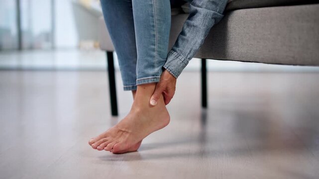 Older Woman Gently Massages Sore Foot While Sitting