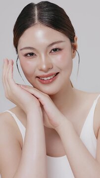 Vertical footage beautiful young Asian woman with healthy facial skin isolated over white background for skincare commercial product advertising. Slow motion shot.
