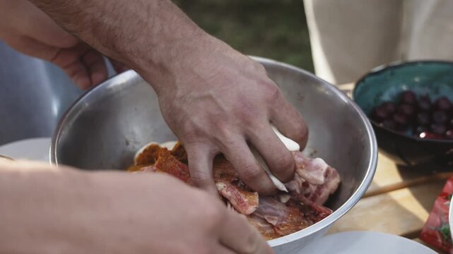 Unrecognizable male hands marinating raw meat in a bowl for barbecue grilling. Concept food preparation, cooking process and kitchen lifestyle.
