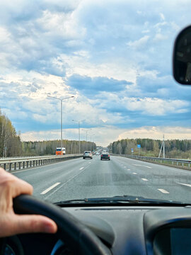 Woman drives solo on a road trip seen through the car windshield focusing on the journey ahead