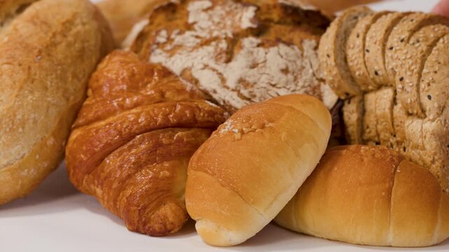 Hands Selecting Sliced Whole Grain Bread from Assorted Bakery Display