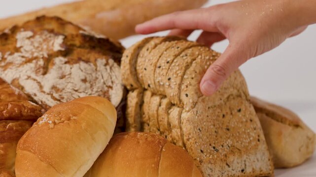 Hand Picking Up Sliced Whole Wheat Bread From Bakery Assortment