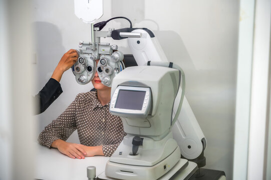 Female patient having eyes examined with an autorefractor machine by professional optician in modern eyewear store