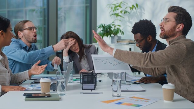 Overworked exhausted business team leader boss woman suffer headache group of managers arguing with paperwork at office briefing. Businesswoman stressed with migraine multiethnic workers argue shout