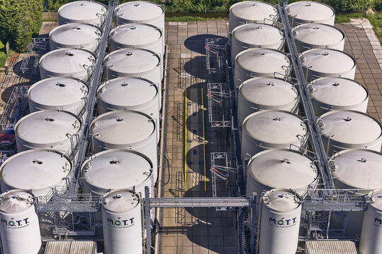 Wormer, Netherlands - 28 April 2026: Aerial view of large white industrial storage tanks for food oils and fats at the M.O.T.T. facility in the Zaan area.