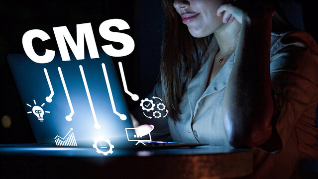 Woman working on a laptop with content management system tools at night in a dark room