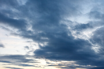 Fototapeta premium Overcast sky with deep blue clouds and golden light breaking through