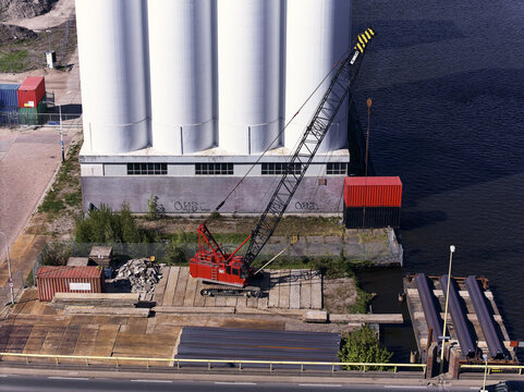 Wormerveer, Netherlands - 28 April 2026: Aerial view of a red sheet piling rig crane and storage area by the Meneba flourmill silos during the Zaankwartier redevelopment project.
