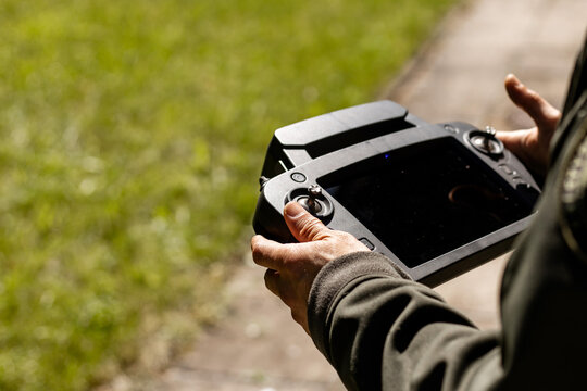 Close up of a pilot hands holding a professional smart remote controller with joysticks and a built-in display screen to operate a drone