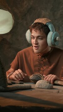 Funny Caveman on Video Call Wearing Headphones and Talking into Prehistoric Stone Axe