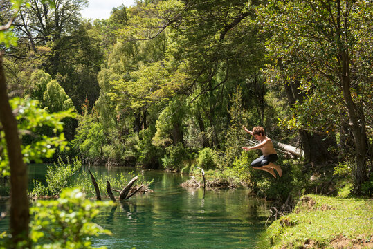 Young man takes a running leap into a river