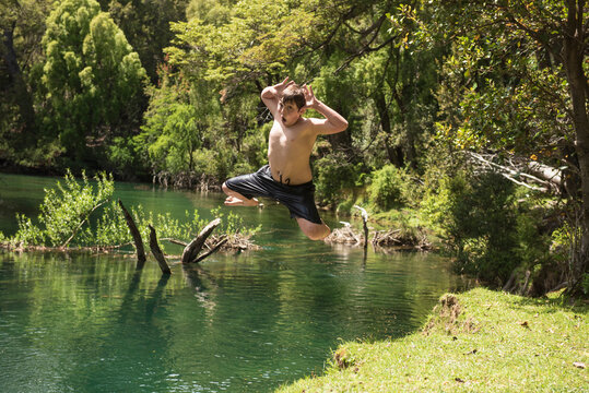Young boy making a funny face jumping into a lake