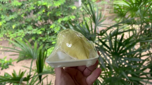 Man holds two pieces of durian on plate