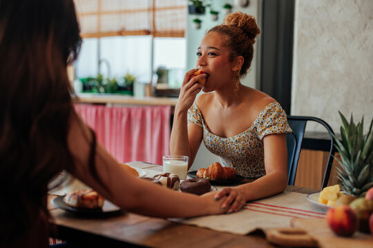 Happy women enjoying breakfast and holding hands