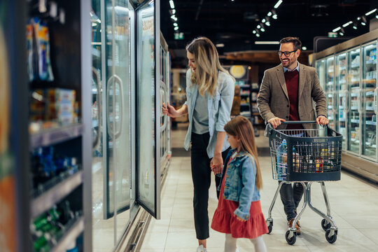 Family shopping for groceries at supermarket freezer section