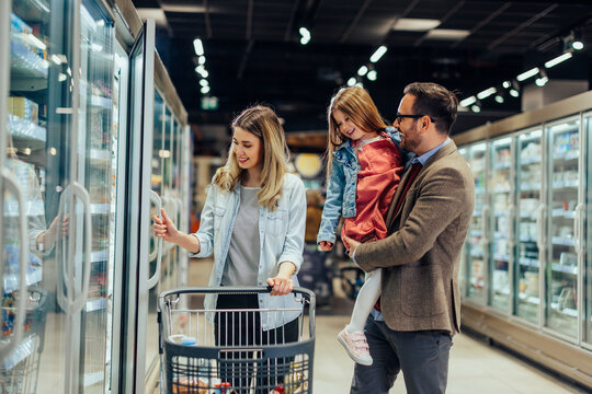 Family shopping for food in the supermarket freezer aisle