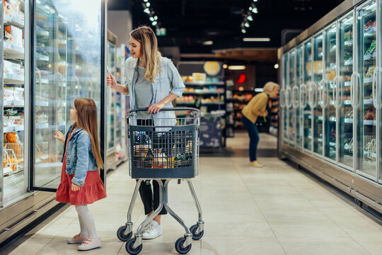Mother and daughter shopping for frozen food in supermarket