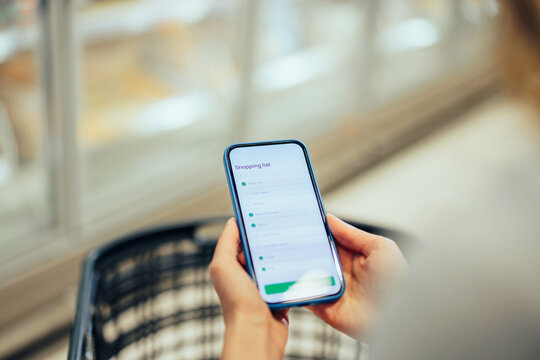 Customer checking shopping list on smartphone in supermarket