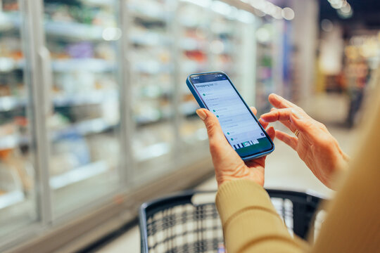 Person checking shopping list on smartphone in supermarket