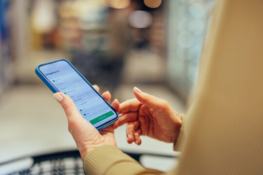 Person checking shopping list on smartphone in grocery store