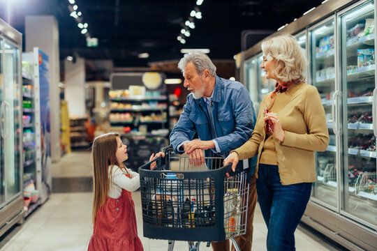 Grandparents and granddaughter talking while grocery shopping