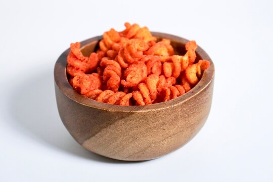 Spicy makaroni spiral indonesian snack in wooden bowl isolated on horizontal white background.