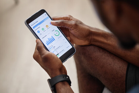 Close up of Black man checking glucose care app on smartphone, monitoring health data and diabetes management. Ideal for telehealth, mobile wellness, chronic care marketing