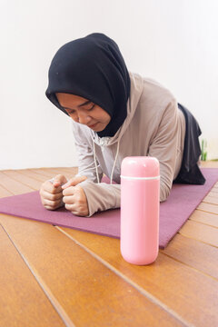 Young jilbab women is exercise at home with tumbler