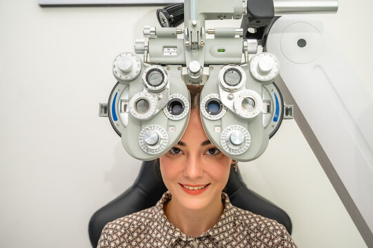 Female patient having eyes examined with an autorefractor machine by professional optician in modern eyewear store