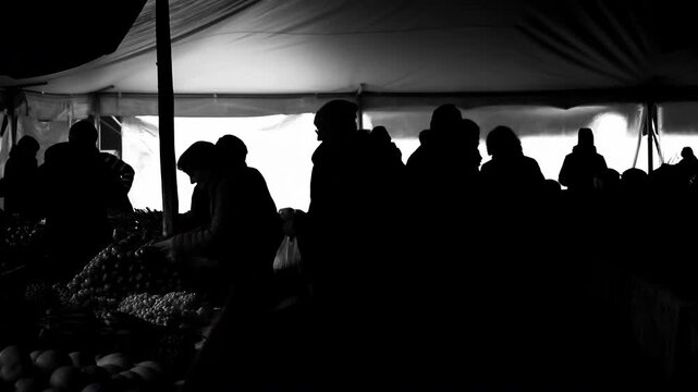 Silhouetted market crowd under tent showing browsing and exchanges across sequence midpoint to end