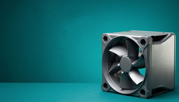 Industrial computer fan on teal background showcasing airflow.