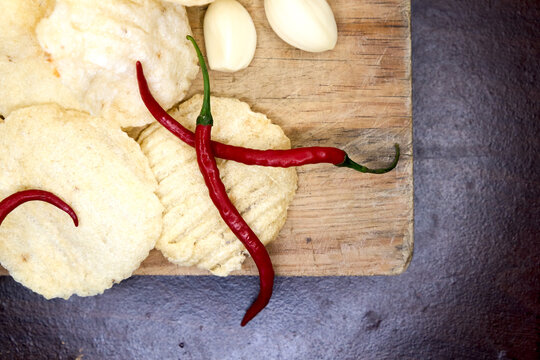 Top view of raw uncooked crackers with red chili and garlic on wooden board.