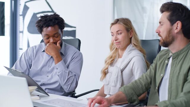 International business group of three workers discussing papers problem African American boss showing folder tablet with document data Caucasian man talk with disagree businesswoman talking in office