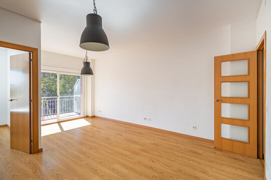 Empty room with wooden floor, large window, and modern pendant light. Bright and spacious interior design with minimalistic style.