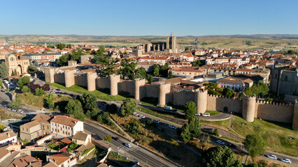 Obraz premium Drone view of Avila city walls long facade with multiple towers and tree lined boulevard in Spain