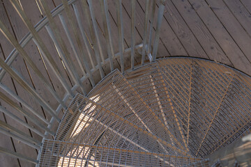 Obraz premium Top view of a metal spiral staircase entry. Architectural abstract of metal stair steps. Close up of outdoor metal spiral staircase